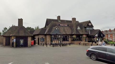 A pub with high sloped roofs viewed from the car park