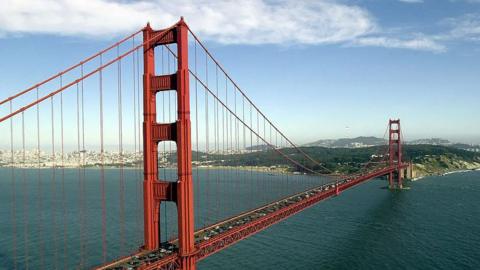 A red suspension bridge across a body of water.