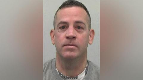 Mugshot of Hodgson. He is clean shaven with a long thin head and short dark hair.