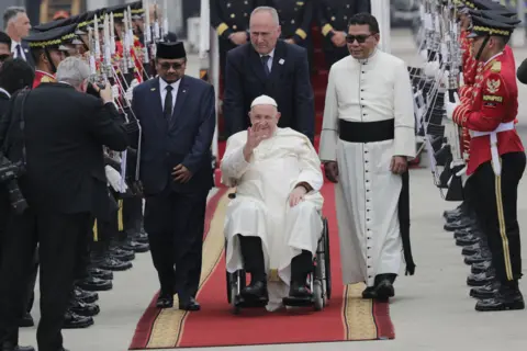 Pope Francis waves during his arrival at Soekarno-Hatta International Airport in Tangerang, Banten, on the outskirts of Jakarta,