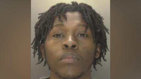 Koketso Ximba - a custody image of a man with black hair in twists