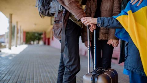 Ukrainian people fleeing with their suitcases 