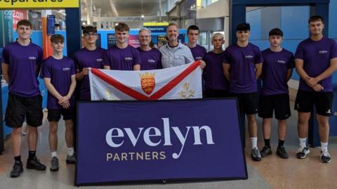 A group of young men wearing purple shirts and holding a Jersey flag