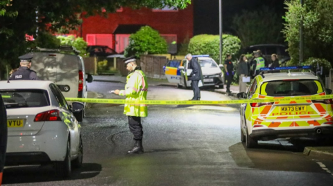 A police office guards a cordon on Aspinall Crescent in Salford