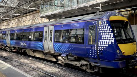 A blue liveried ScotRail trainsits at a platform. We can see three carriages.