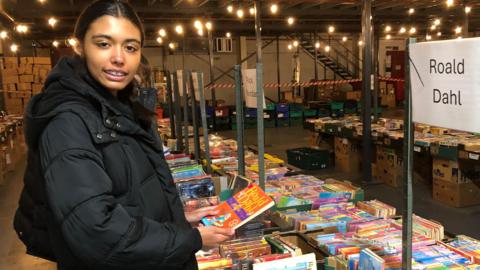 Sophia stood next to a table full of books holding a book by author Roald Dahl