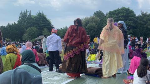 Muslim women dressed in their abayas and head scarfs sitting in preparation for eid prayers in the park