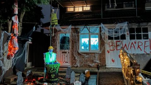 Skeletons wearing hi-vis jackets, BEWARE painted in fake blood on garage doors, gravestones and spider webs on the front drive of the house. 