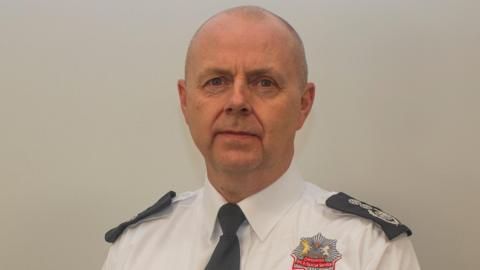 Mick Sharman in a white shirt and black tie