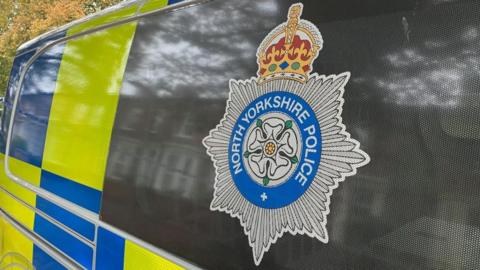 North Yorkshire Police logo on the side of a van with trees just visible behind the vehicle.