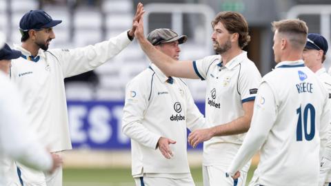 Ben Aitchison high fives a Derbyshire team-mate after taking a wicket against Middlesex at Lord's