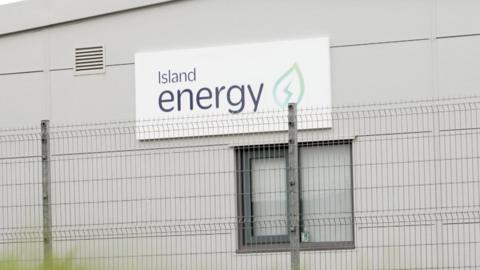 An Island Energy sign on a warehouse, with a fence in front of it.