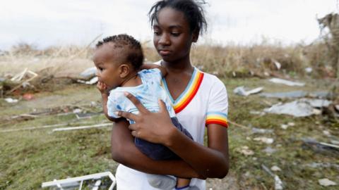 Moheisha McDonald holds her baby brother Ozieion Foster after Hurricane Melissa made landfall, in Black River, Jamaica, October 30, 2025.