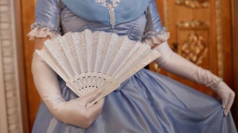 Close up of lady wearing blue ballgown curtsying