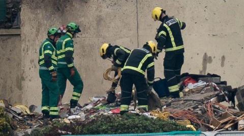 A picture of emergency services at the scene of the explosion in 2022, they are looking through rubble on the ground