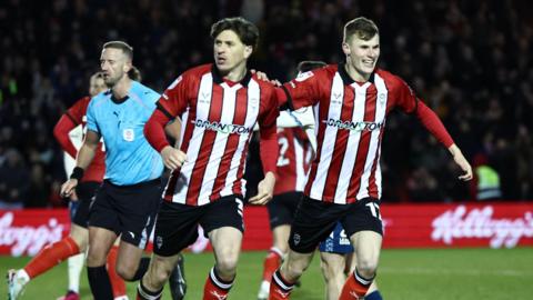 Adam Reach (left) runs alongside team-mate Rob Street who smiles and holds his arm on Reach's shoulder