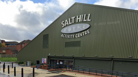 Salt Hill Activity Centre is a triangular, dark green building with a few steps leading down to the main entrance.