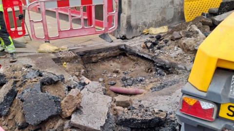 An area of dug up and broken Tarmac.