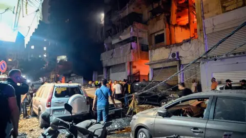 People gather in front of a damaged building after an Israeli military strike at the Nuwayri area in Beirut, Lebanon, 10 October 2024. 