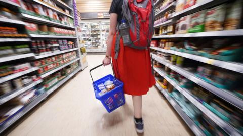 A shopper walking through the aisle of a supermarket.