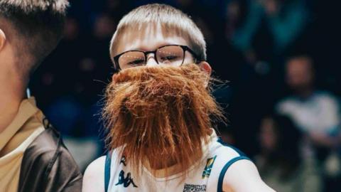 Young Caledonia Gladiators fan, Max Philliban, dressed as head coach, Gareth Murray, wearing a large beard.