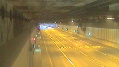 A National Highways traffic camera showing an empty road in a tunnel lit by streetlights