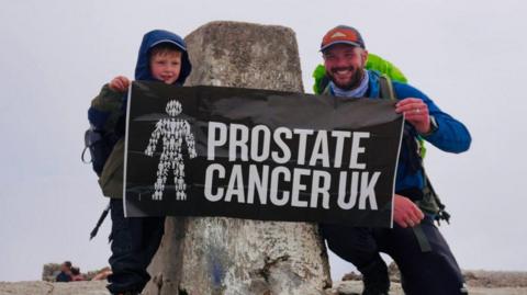 Jasper Dunsmore and Peter with a Prostate Cancer UK flag