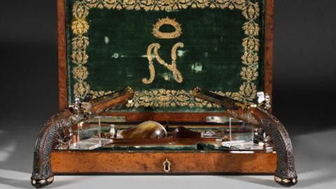 Two pistols stand in front of a wooden box