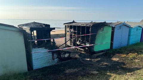 Colourful beach huts with some blackened by fire 