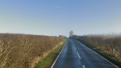 The road is a rural A road, and from the direction the photo was taken is looking up the brow of a hill on a sunny day.