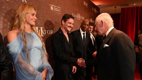 King Charles shaking hands with Pedro Pascal, with Connie Nielsen, Denzel Washington and Paul Mescal standing nearby