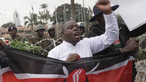 A protester holds a Kenyan flag during a demonstration in front of Kenya's Parliament on June 25 2026. 