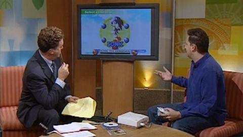 Presenters look at Sonic the Hedgehog on the Sega Dreamcast.