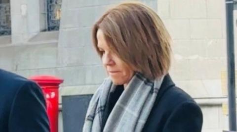 Dawn McIntosh leaving court, she is wearing a dark jacket and a grey scarf.
