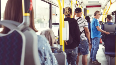 People stand and sit on a bus