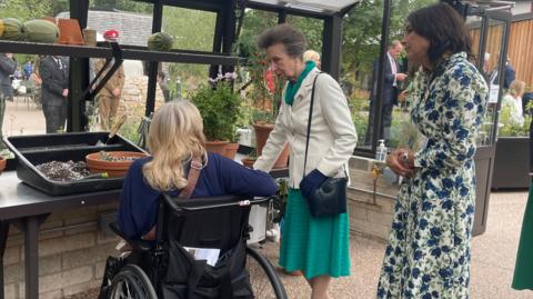 Princess Anne greeting a patient of the Princess Royal Spinal Injuries Centre, part of the Northern General Hospital, in the greenhouse of its new garden.