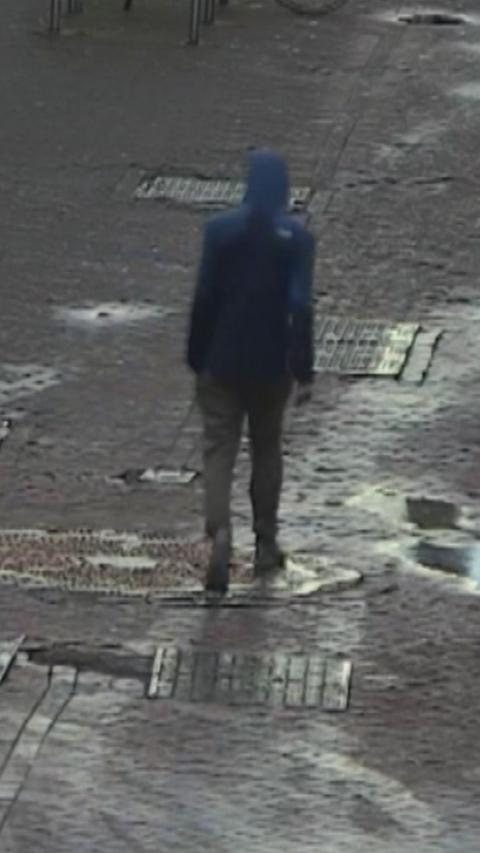 CCTV of a man in a dark hooded jacket, walking down an Edinburgh street