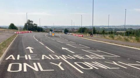 A empty new road with "ahead only" written on the tarmac in white letters