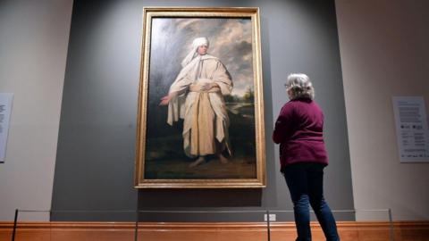 Portrait of Mai by Sir Joshua Reynolds in Cartwright Hall. A woman stands in front of the painting, admiring it.