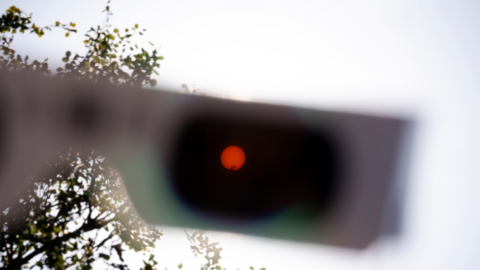 An orange sun seen through a pair of black paper eclipse glasses. 
 