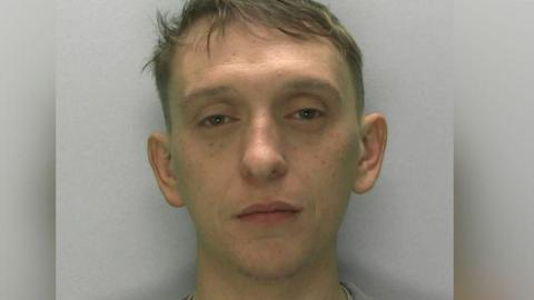 Custody picture of Andrew McQueen. He is clean shaven and has freckles and blonde hair 
