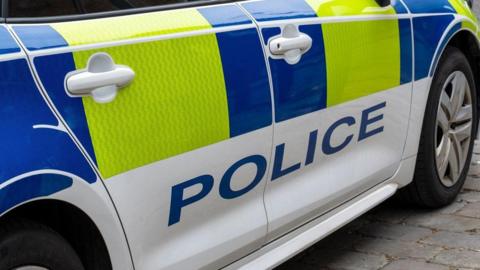 White police car with blue and yellow markings and POLICE in large blue letters.