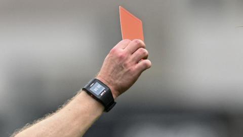 A hand holds up a red card. 