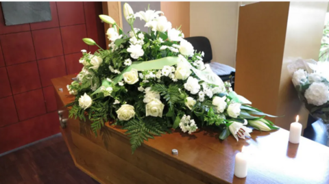 A coffin with a wreath on top 