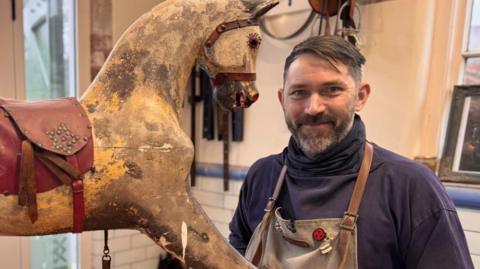 Rocking horse restorer Peter Rix stood with a century-old rocking horse.