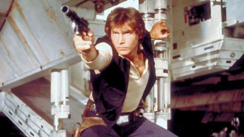 Han Solo in a screen grab from Star Wars. He has a phaser in hand about to shoot and is holding the open exit ramp to the millennium falcon