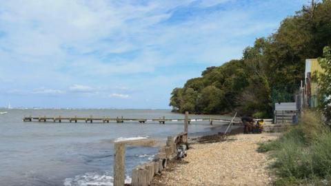 A shingle beach with a wooden jetty