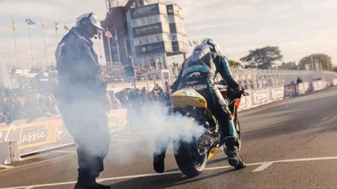 Michael Dunlop on the start line at the grandstands with crowds watching.