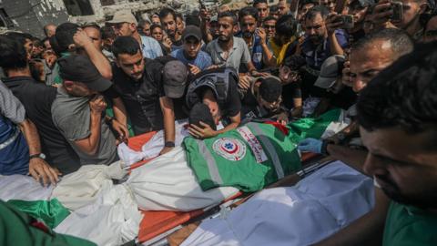 A crowd of men gather around the shroud covered bodies people who were killed during Israel' stargeted attack on Gaza City on Sunday night. 