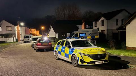 A Police car on a dark residential street at night.